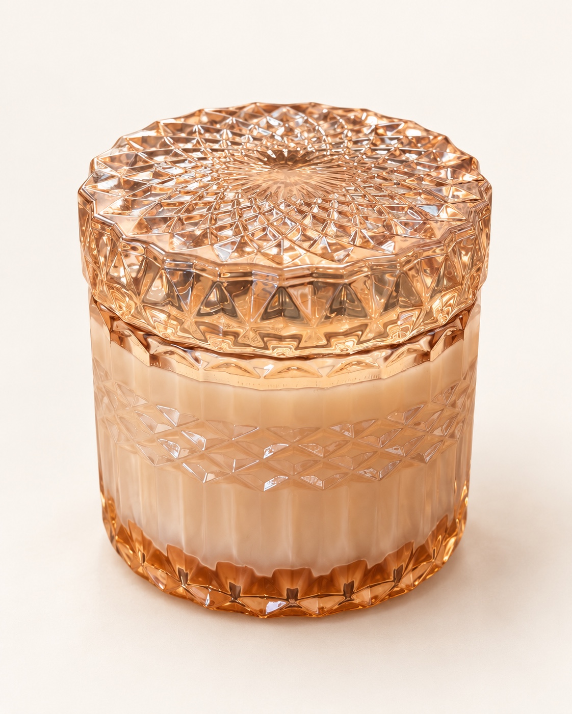 Rose-toned faceted glass candle jar with a matching decorative lid.