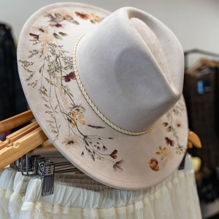 Ivory wide-brim hat with delicate botanical illustrations and a braided band.